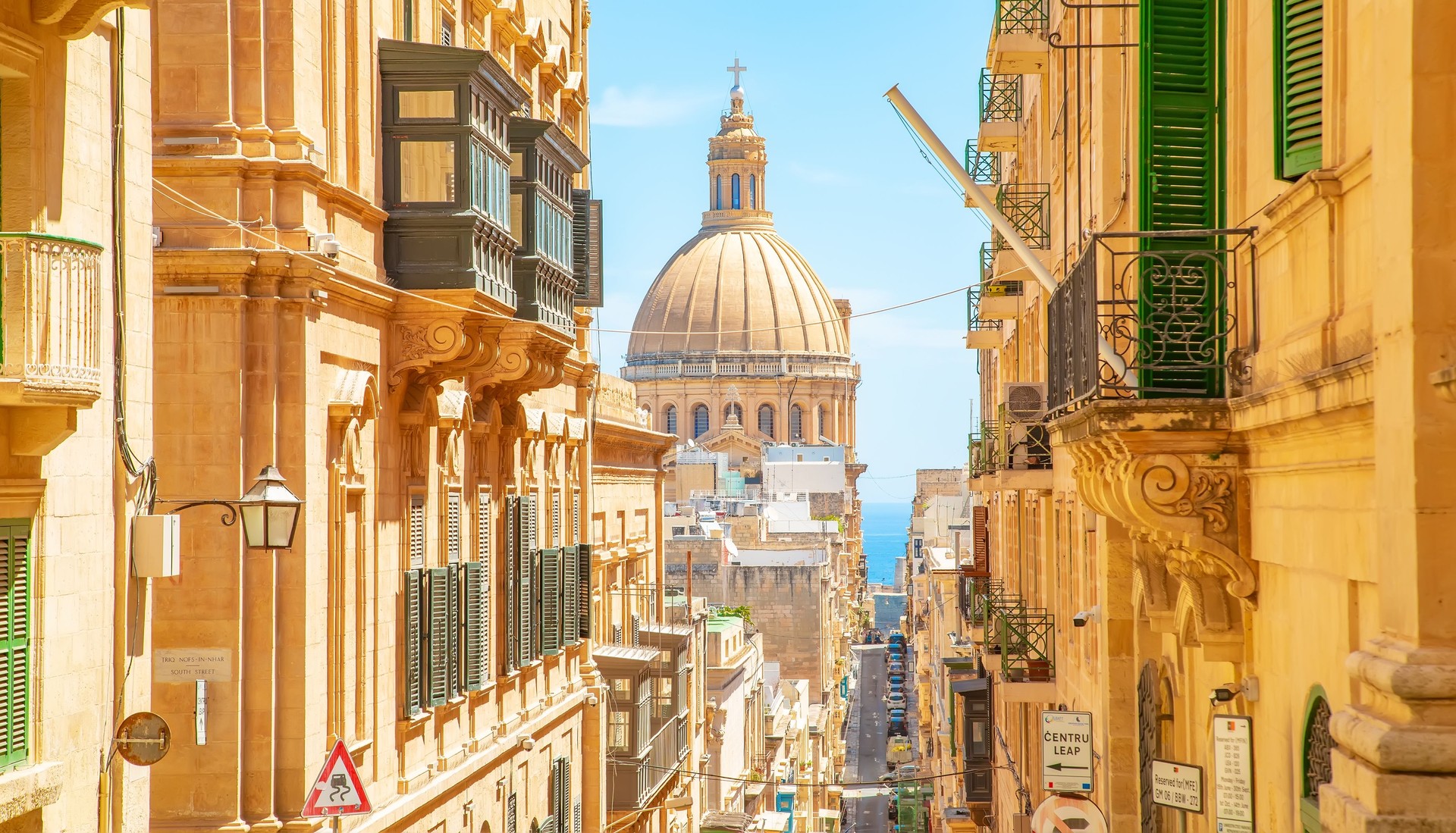 Sunny street in Valletta old town, Basilica of Our Lady of Mount Carmel on a background, Malta